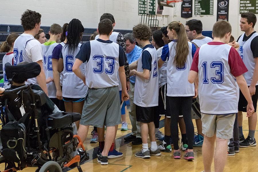 Members of the unified team gather around coach Milton Robinsion prior to a home game earlier this season.