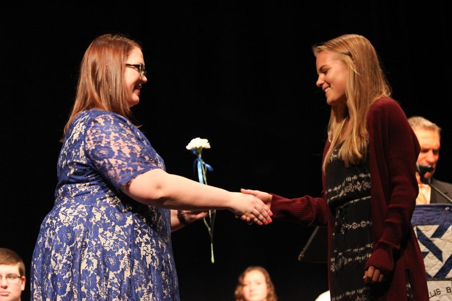 Rebecca Ide 18 receives a flower from advisor Elissa Johansson.