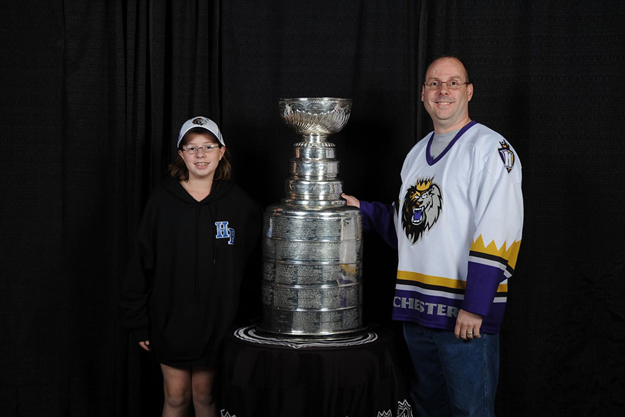 After waiting for almost 2.5 hours outside with all other season ticket holders for the AHL team Manchester Monarchs, the trophy shined under the lights. Emily Mitchell ‘18 and her father take a photo with the Stanley Cup won by the LA Kings in 2012. 
