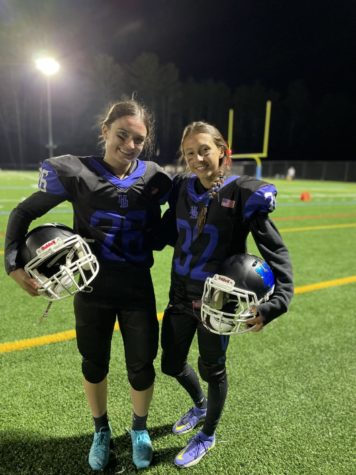 Claire Ballou and Keira Swart, soccer teammates and friends for more than a decade, smile for a photo together on the football field.