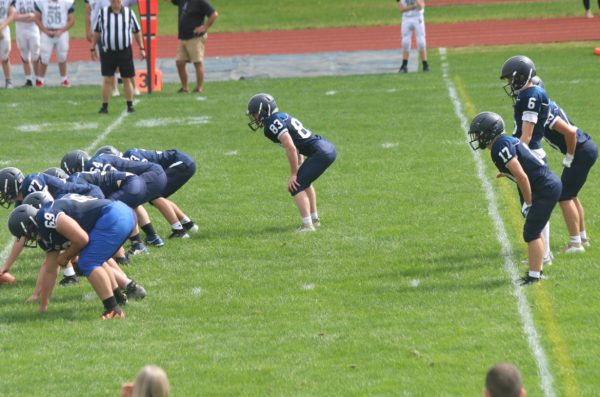 Spartans players at the Milford High School field about to begin next offensive play. Athletes will rally tonight at Hollis-Brookline to fight for a win. “A captain has to set the tone, show the other guys what they have to do. Everyone's looking at them,” Tessier ‘25 said. 
