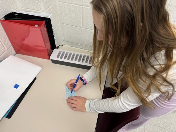 Addison Marchant ‘25 fills out a hall pass right before going to the bathroom during AP Statistics class.