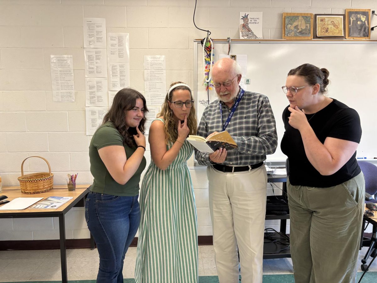 
(Left to right) Kaylee Barchard, Heather Hamilton, Michael Fox, and Tori Flaherty intently study Fox’s current read, Time is a Mother. They began the NEHS and dedicated it to Fox because of a shared love for reading and the English language. “NEHS is going to provide the space for kids to see the power of connection that great literature and love of it provides,” Flaherty says. 
