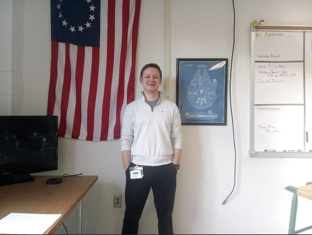 Mr. Portu, standing in the front of the classroom, right next to his teaching spot. The poster of the Millenium Falcon is one of his favorites in the room.
